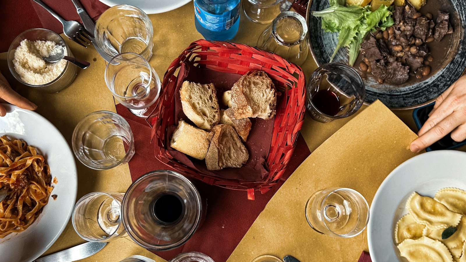 An Italian table set with bread, wine, ravioli and shared plates